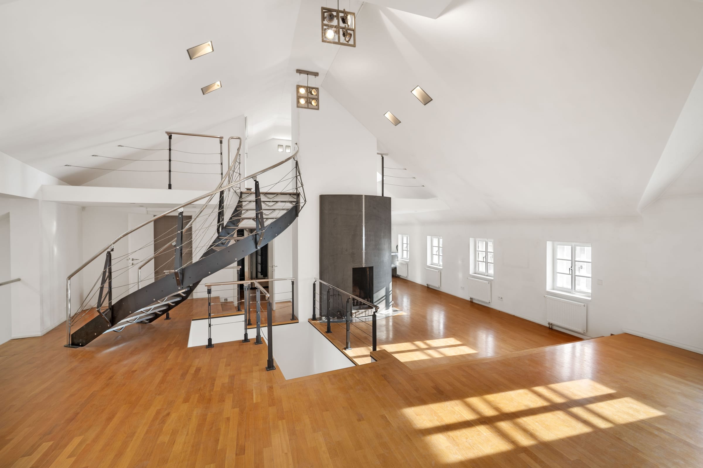 Attic: hall with oak floor, steel spiral staircase and the cylindrical fireplace