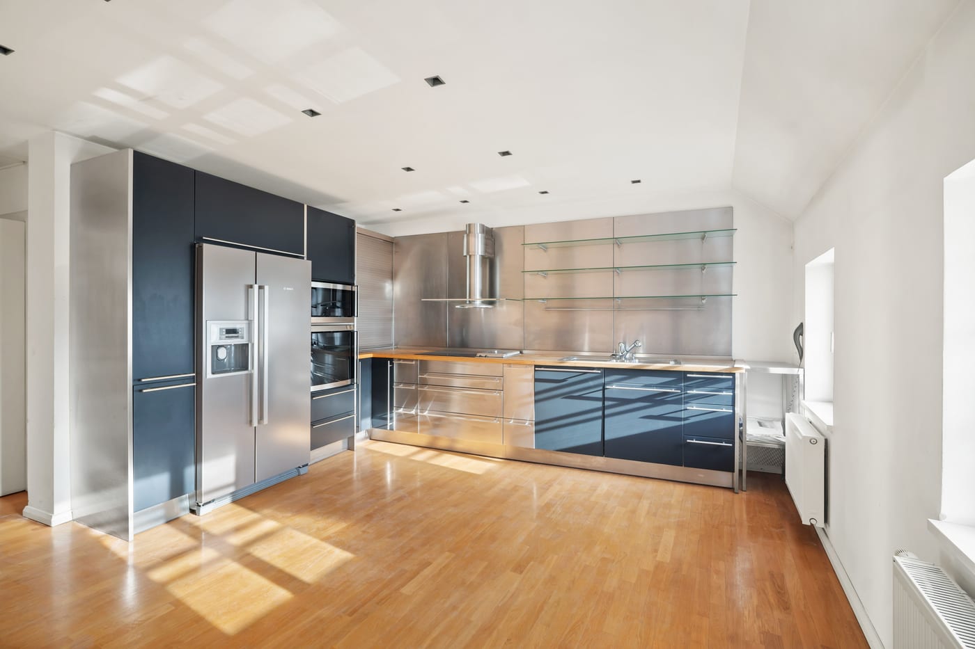 Custom kitchen in the attic: stainless steel units, built-in appliances, oak floor