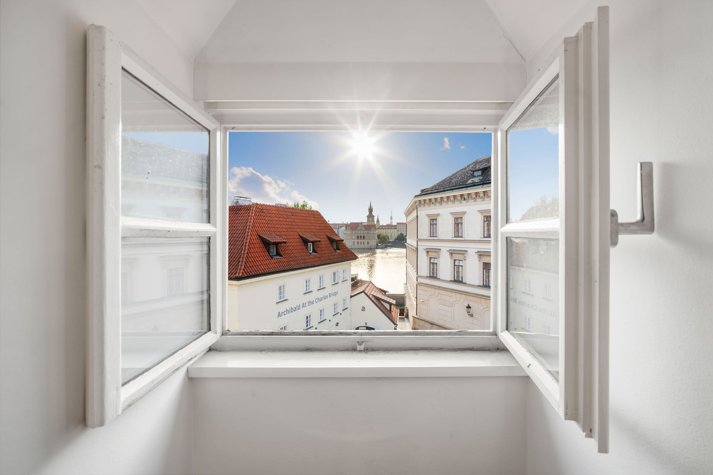 Open window with a view of the roofs and the Vltava